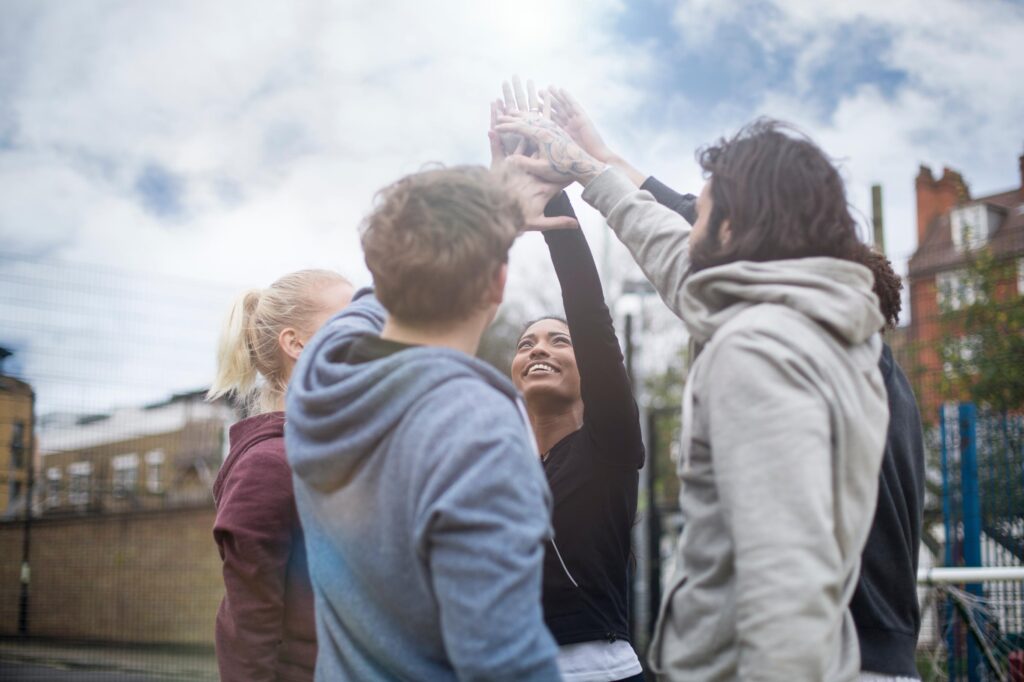 Corporate team building participants celebrating with a group high-five during an outdoor team-building adventure, promoting collaboration, communication, and team spirit.