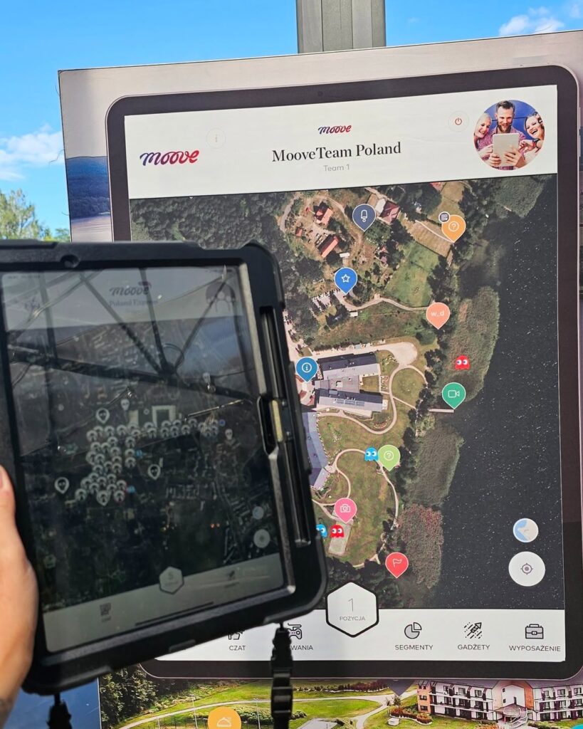 A rugged tablet and event display showing a gamified map with challenge points during a Mooveteam activity.